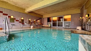 An indoor swimming pool with tiled walls and multiple shower stations. - Kidoike Onsen Hotel (Yamanouchi)
