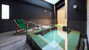 A modern spa area with a hot tub, wooden deck, and a green lounge chair. - Onyado Megumi (Yugawara)