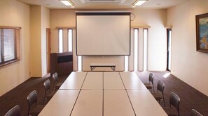 A conference room with a long table, chairs, a projector screen, and windows. - Onyado Megumi (Yugawara)