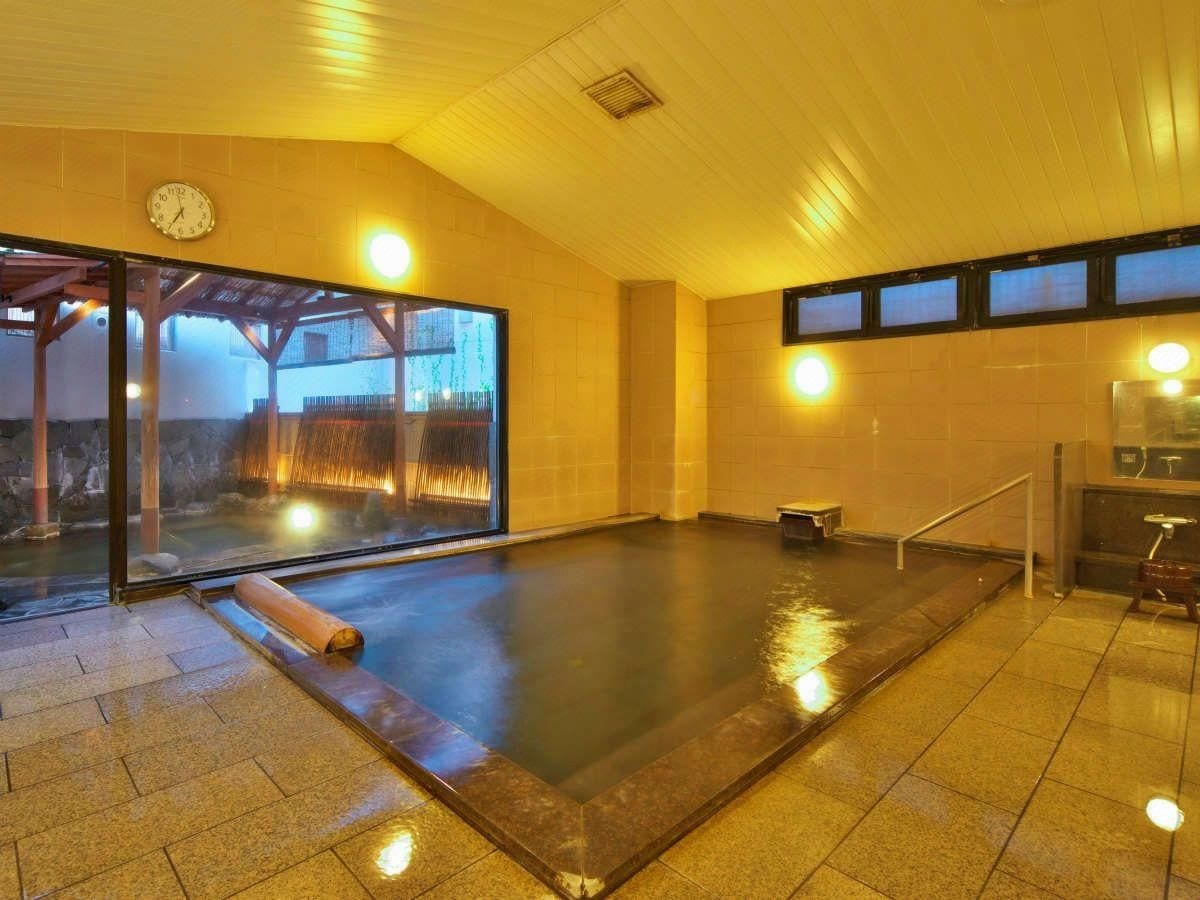 A hot spring bath with a glass enclosure, a clock, and a view of a building outside.
