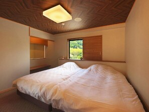 A bedroom with a bed, a window, a wooden ceiling, and a wall-mounted light fixture. - Onyado Megumi (Yugawara)