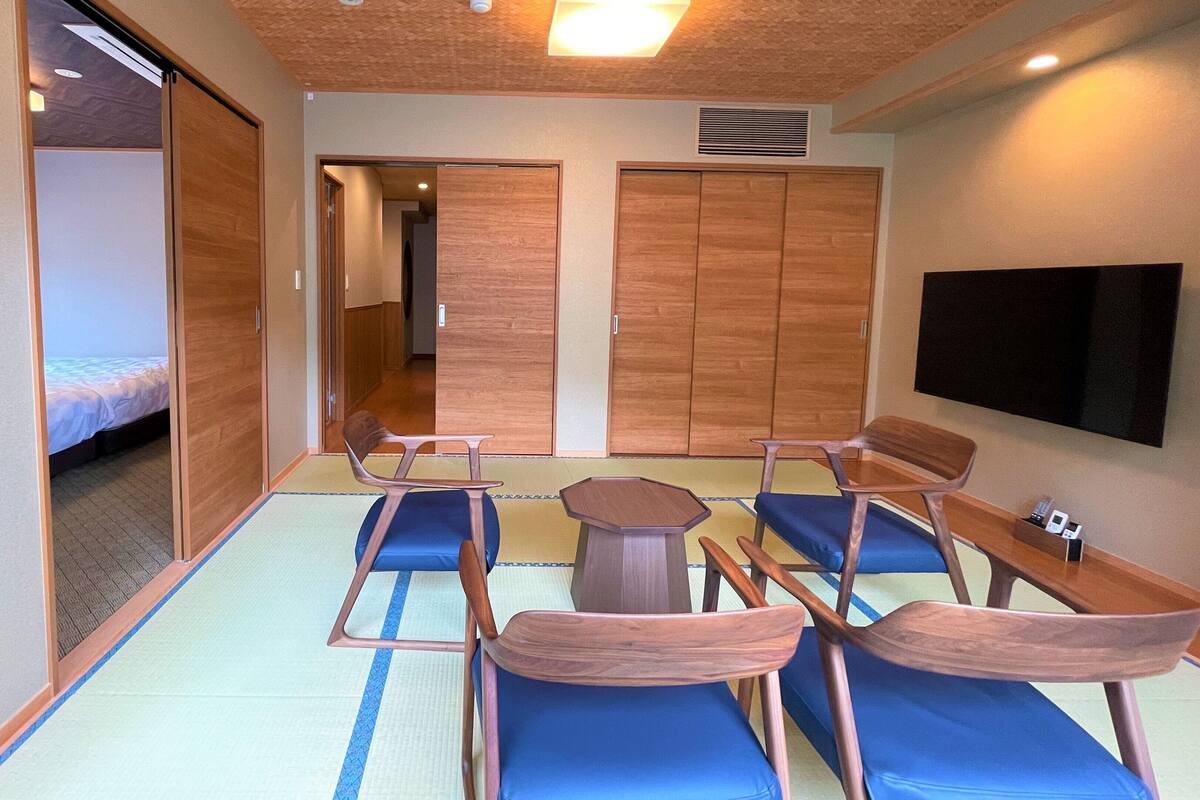 Quarto com esteiras de tatame, cama, televisão e mobiliário de madeira.