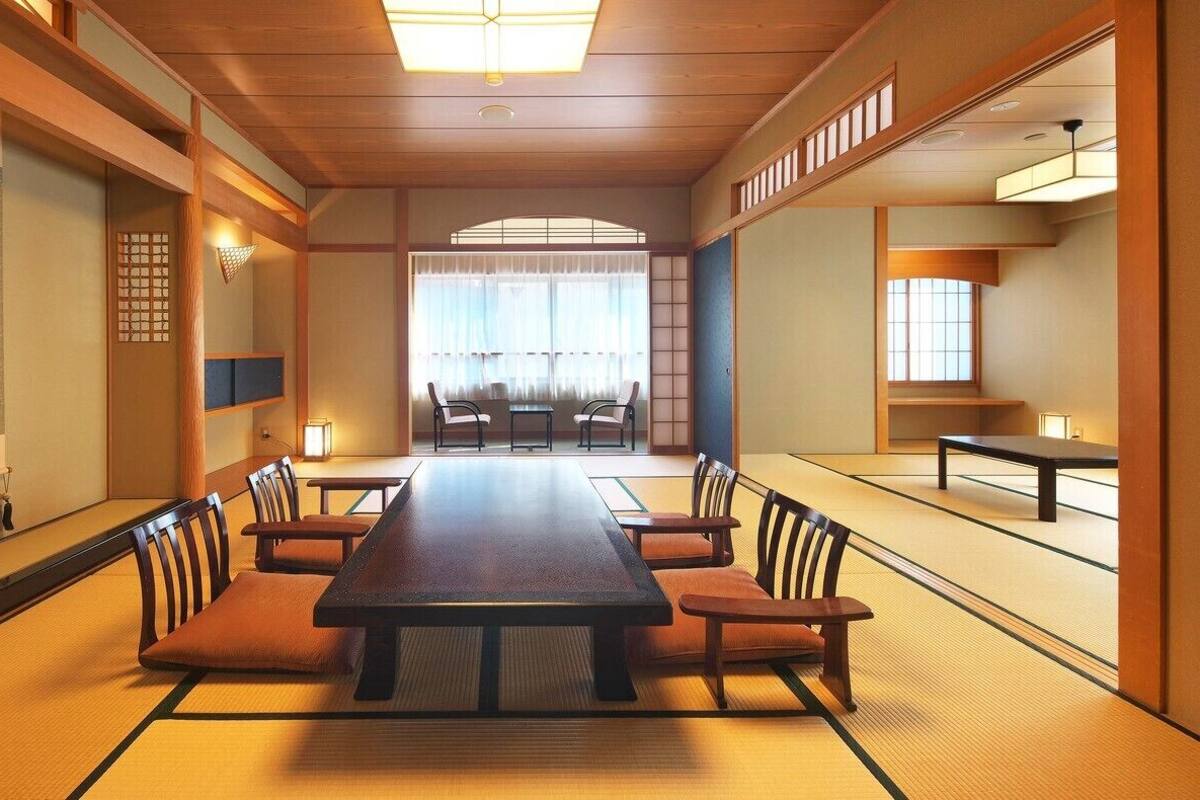 Um quarto japonês tradicional com tatames, uma mesa baixa e cadeiras de madeira.