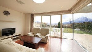 Un salón amplio con un ventanal grande, un televisor de pantalla plana, un sofá y una mesa de centro.