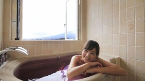 Un baño con bañera, ventana y pared de azulejos.
