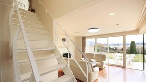 Un interior moderno con una escalera, un sofá y vistas al exterior.