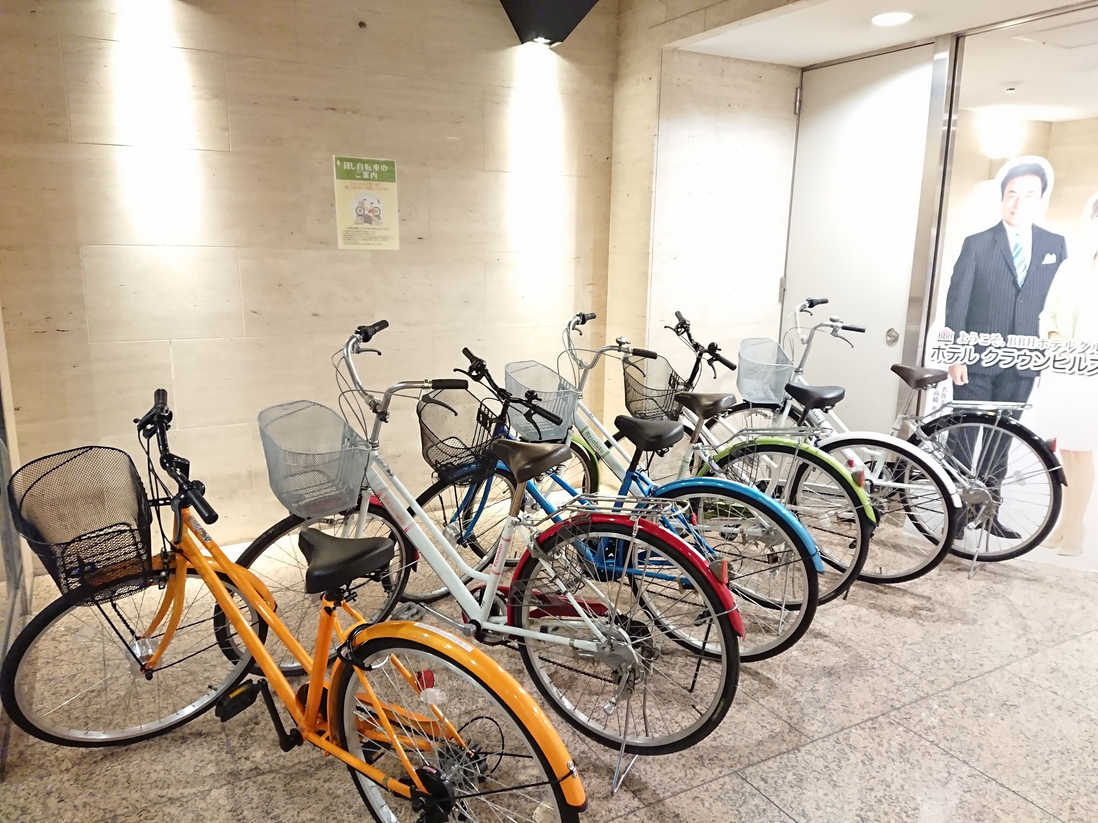 Varias bicicletas estacionadas en un interior, con piso de baldosas y una pared con un cartel.