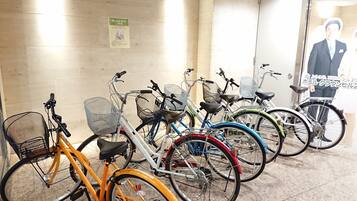 Varias bicicletas estacionadas en un interior, con piso de baldosas y una pared con un cartel.