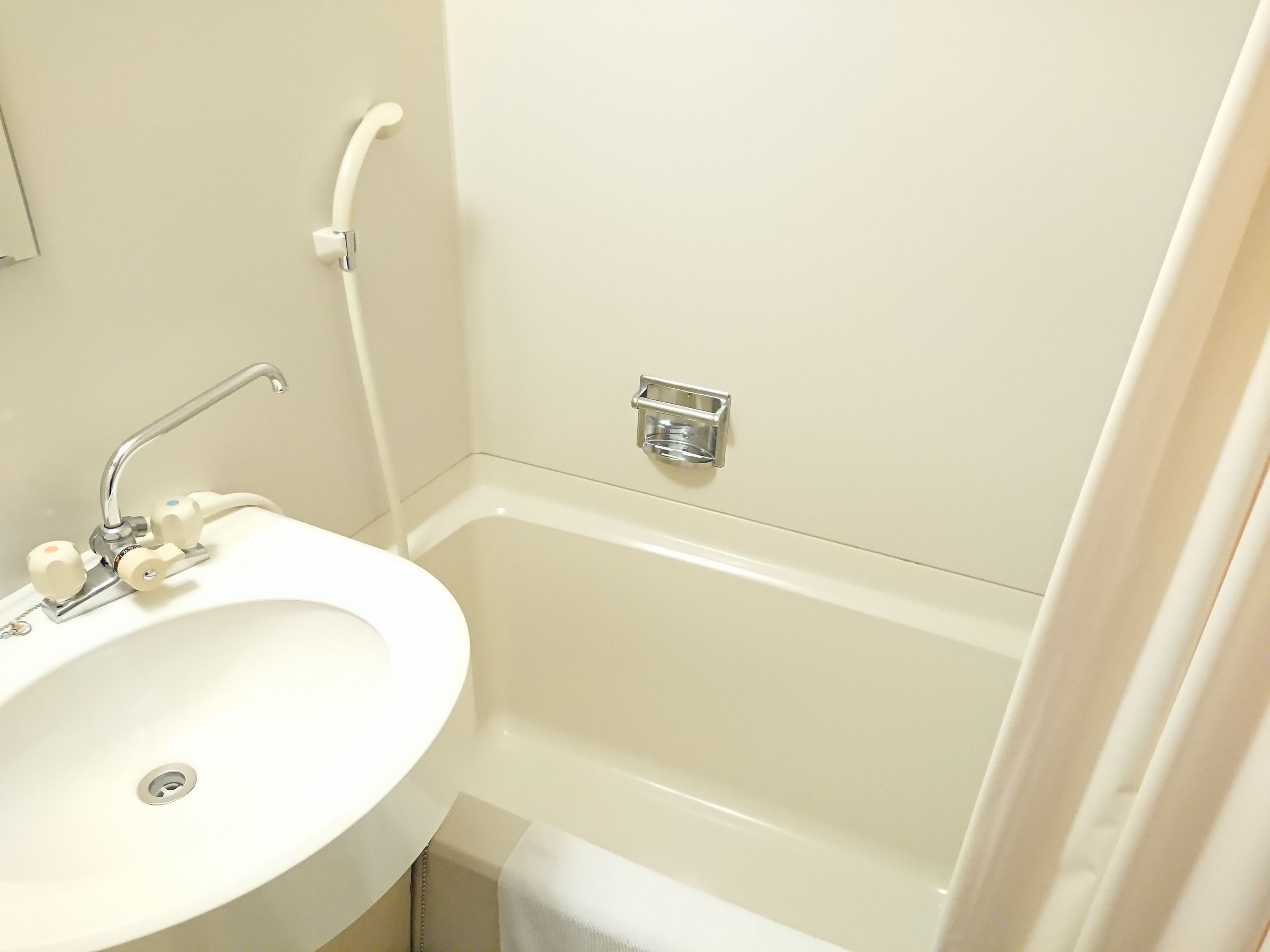 A bathroom with a white sink, a bathtub, and a shower head.