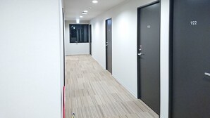 Un pasillo con suelo de madera, paredes blancas y puertas con los números 922 y 923.