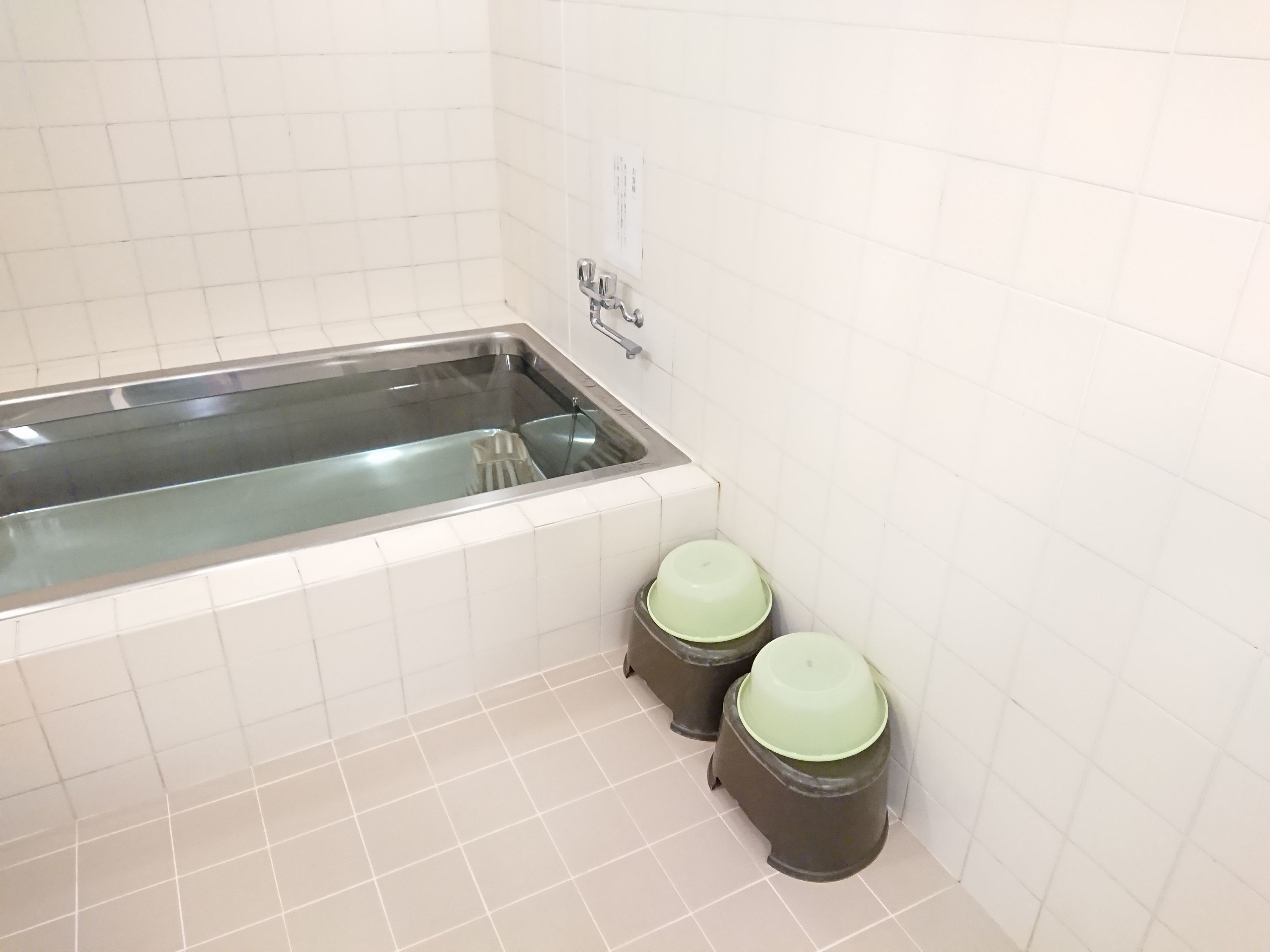 Ein Badezimmer mit einer Badewanne, zwei Mülleimern und einem Wasserhahn.