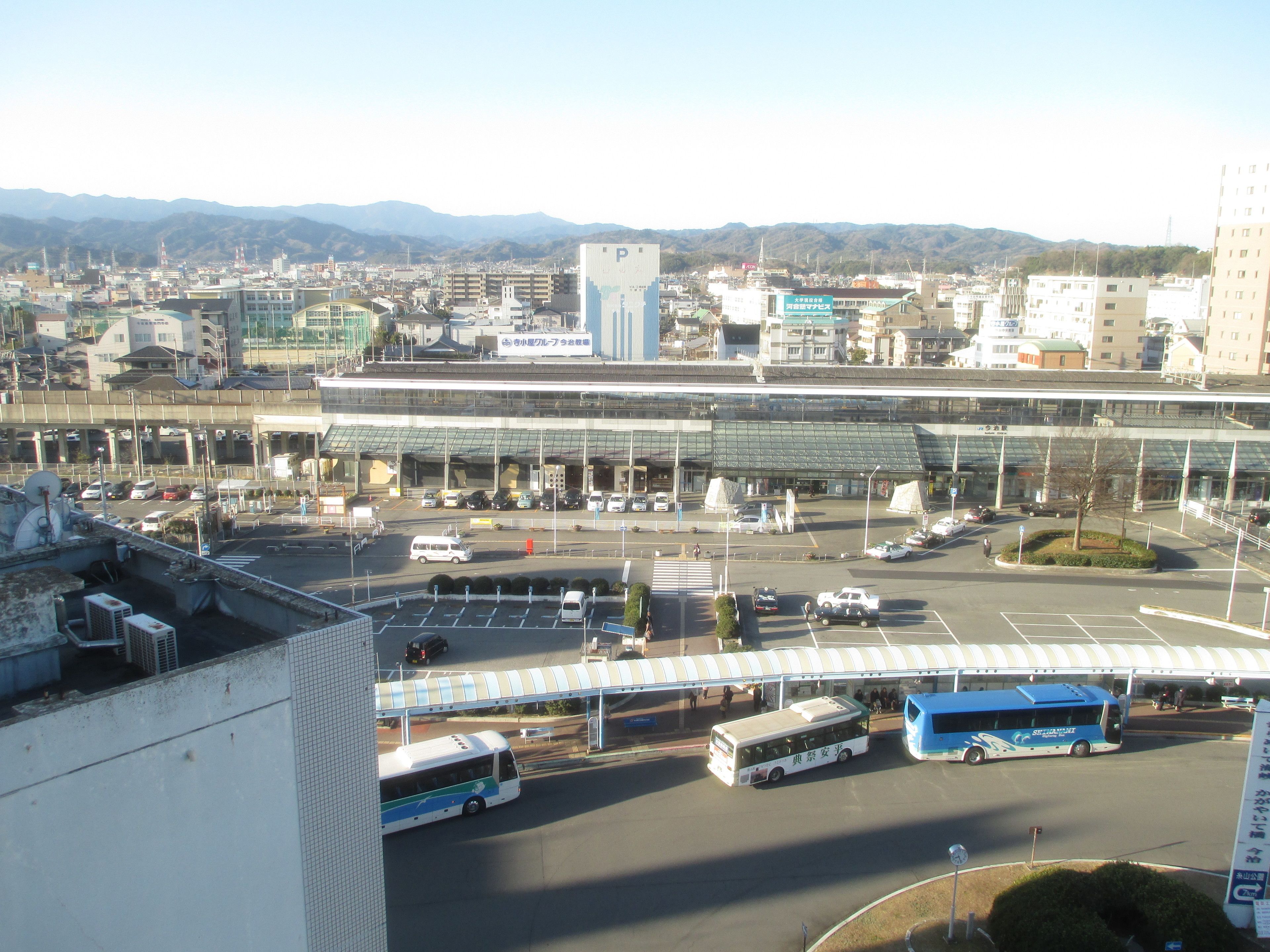 A large airport terminal with multiple gates, a bus station, and a parking area.