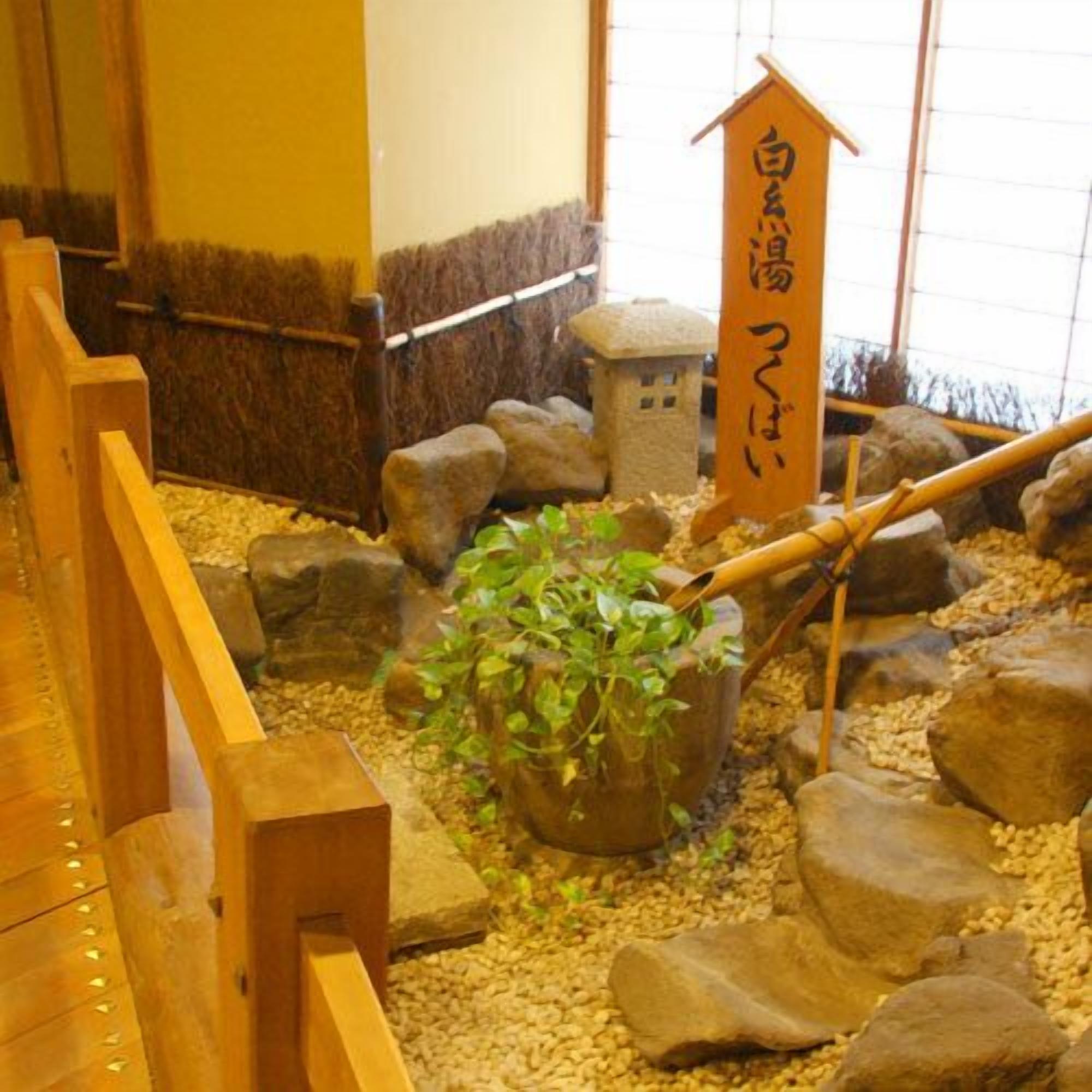 Une structure en bois avec une pancarte, des rochers et une plante en pot.
