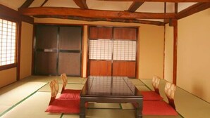 Una habitación japonesa tradicional con suelo de tatami, una mesa baja, puertas correderas y una lámpara colgante.