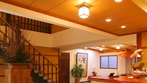 Un interior amplio con una escalera de madera, un mostrador de recepción y un suelo a cuadros.