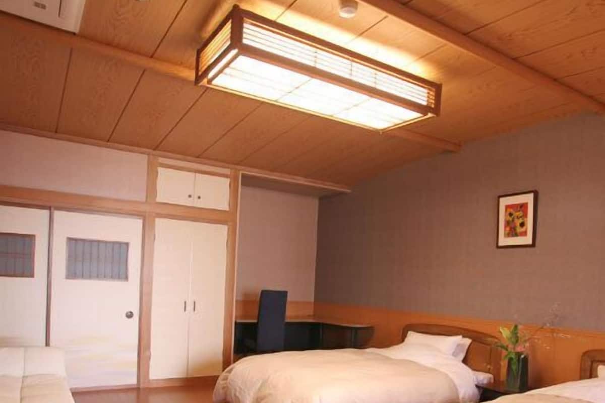 Una habitación de hotel con dos camas, un escritorio, una silla y un armario.