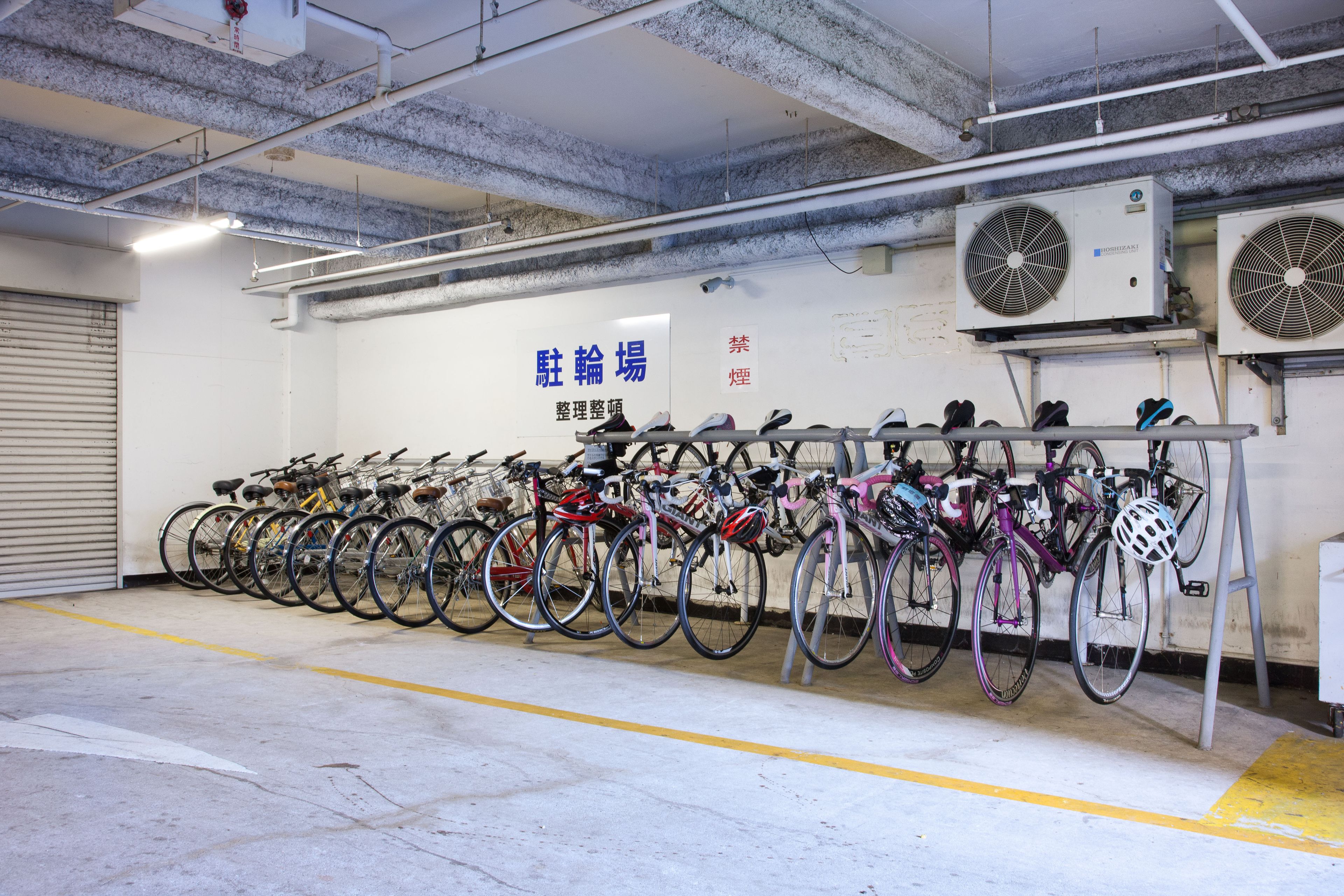 A bicycle parking area with multiple bikes and a ventilation system.