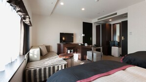 Una habitación de hotel con cama, sofá, escritorio, televisor y espejo.