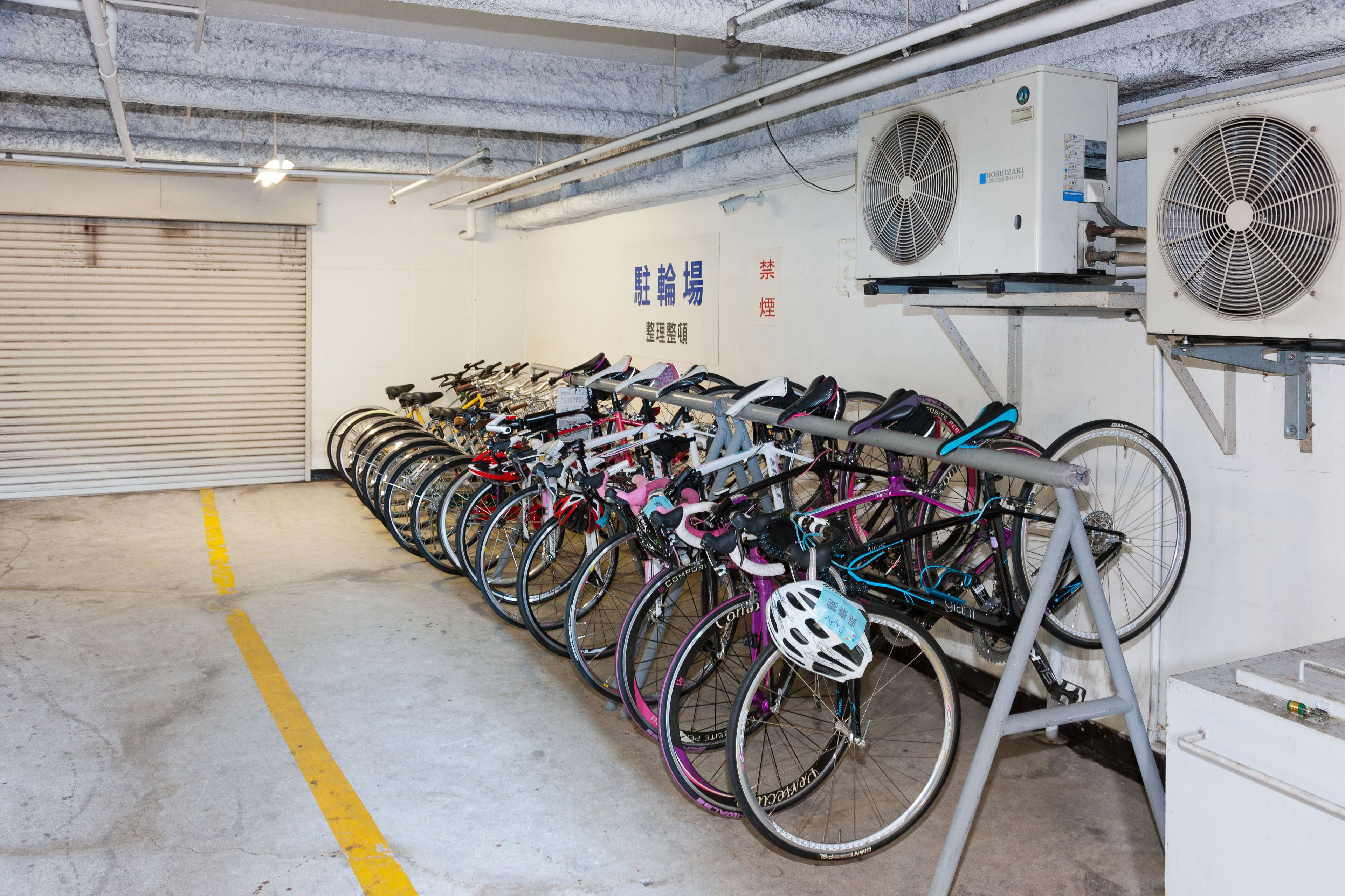 A bike rental facility with multiple bicycles and fans on the wall.