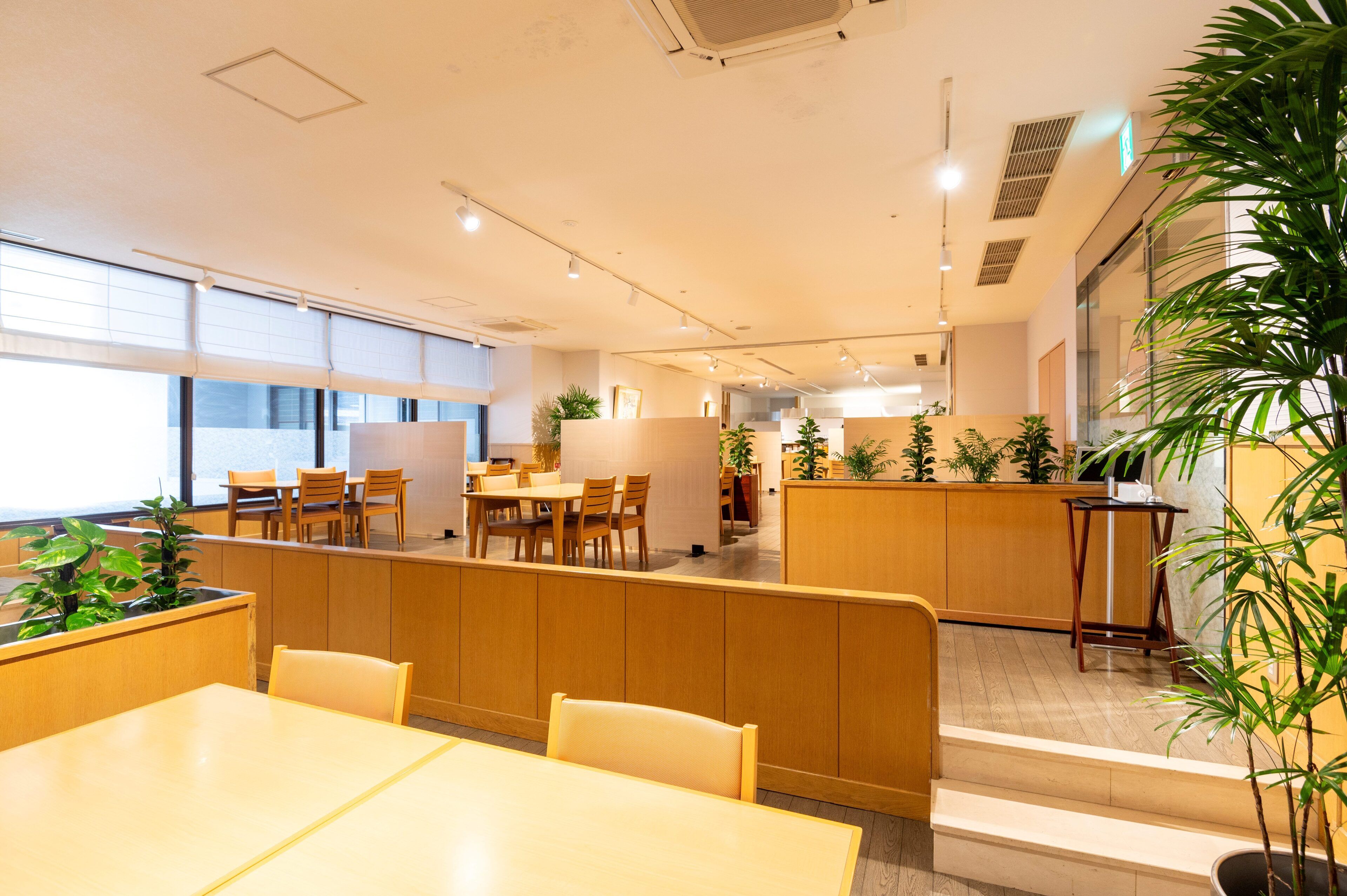 A modern interior with wooden furniture, large windows, and indoor plants.