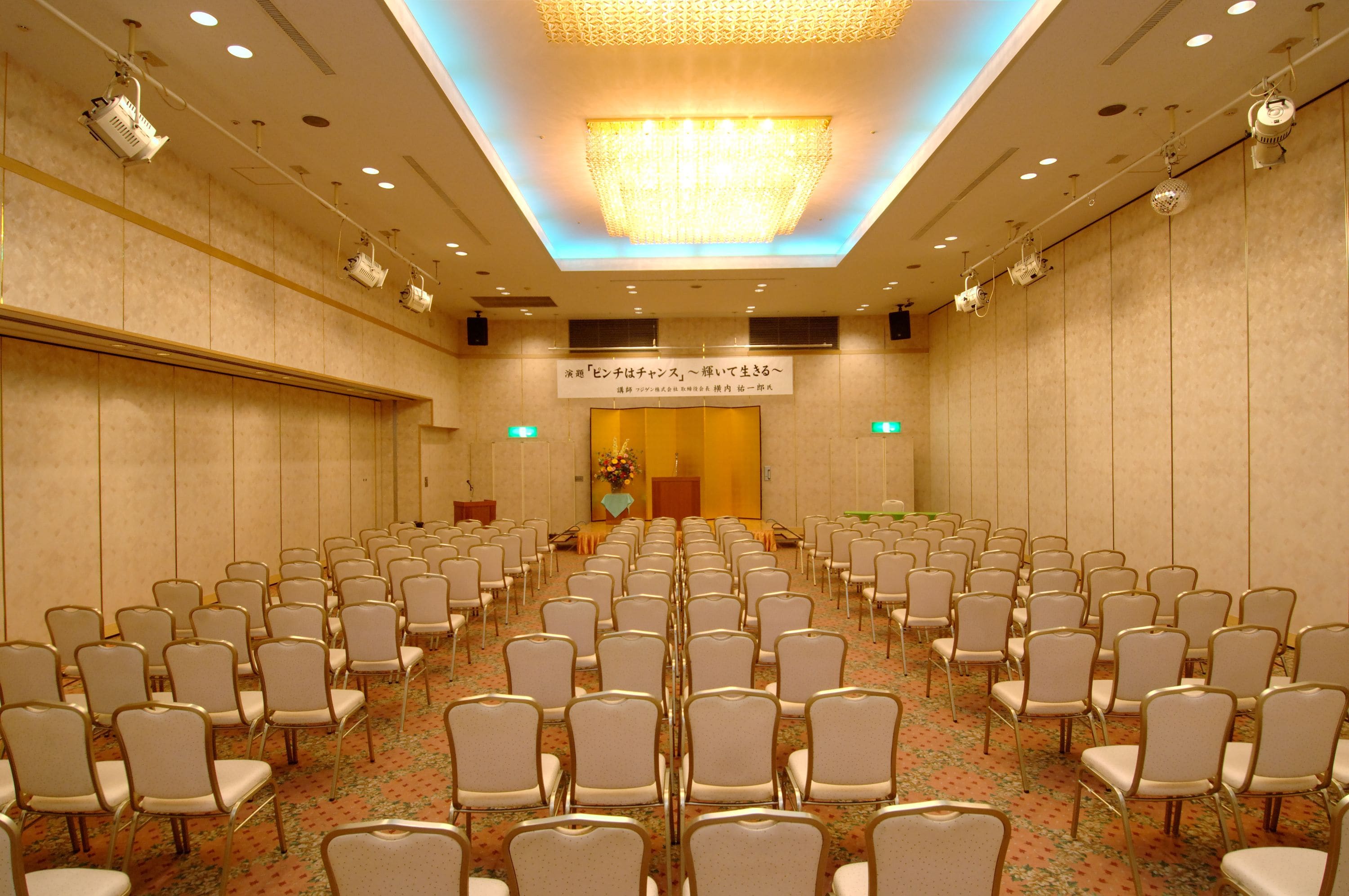 A conference room with rows of chairs, a podium, and a floral arrangement.