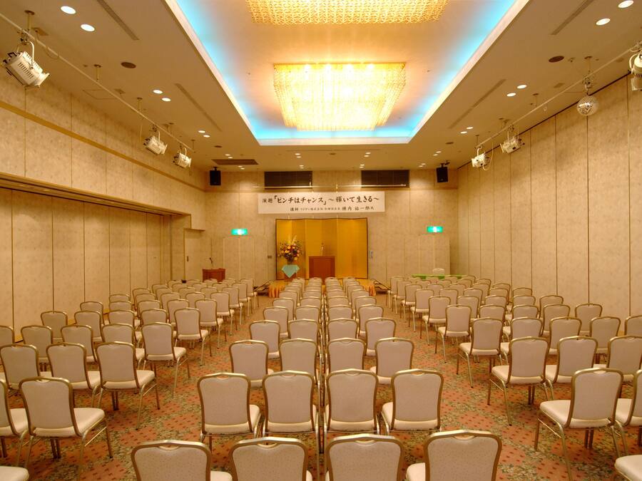 A conference room with rows of chairs, a podium, and a floral arrangement.