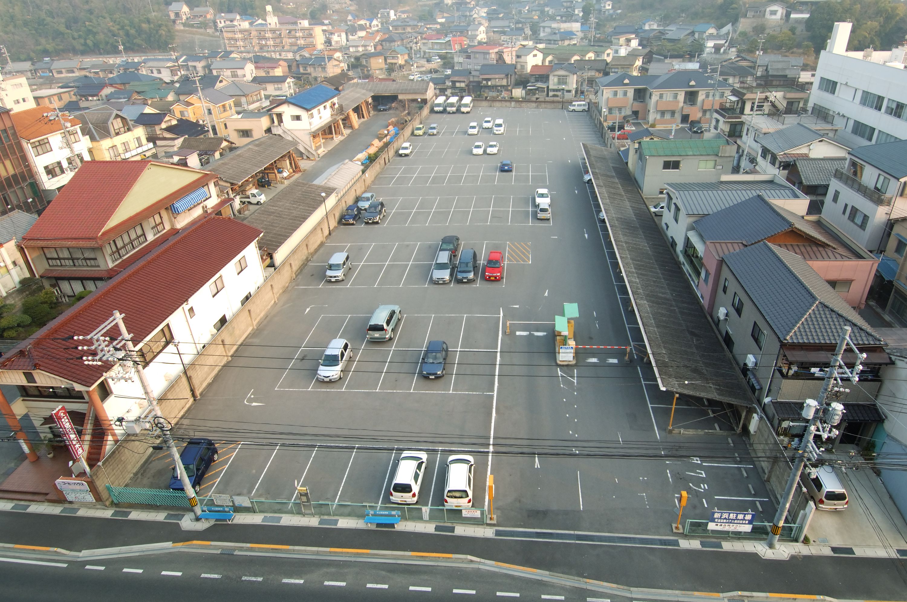 An aerial view of a parking lot with multiple cars and buildings surrounding it.