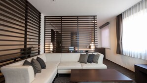 Una habitación de hotel moderna con sofá modular, una mesa de centro y un televisor.