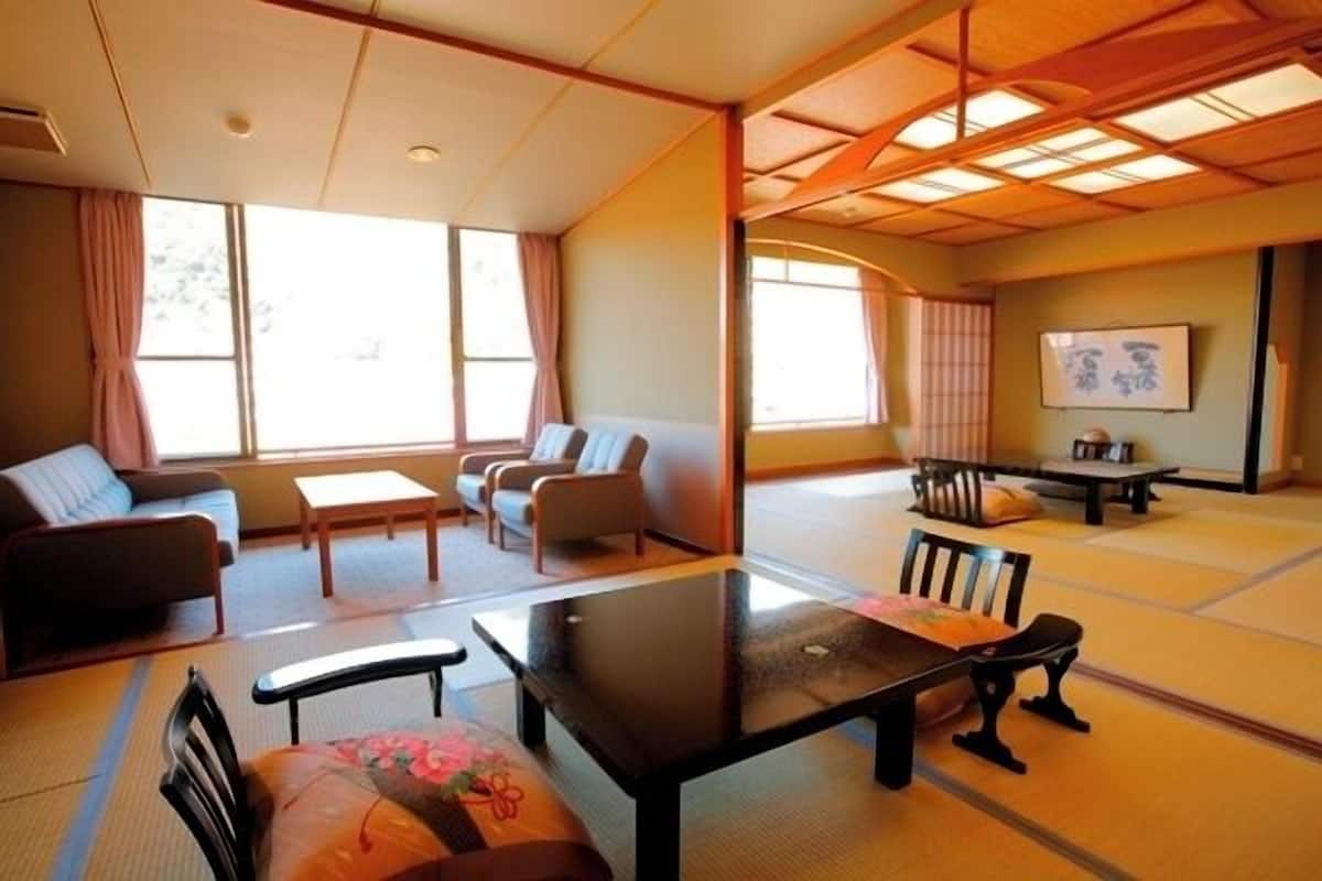 A traditional Japanese room with tatami flooring, a low table, and seating arrangements.