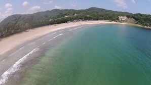 Vista sulla costa con spiaggia, acqua limpida e edifici sulla collina.