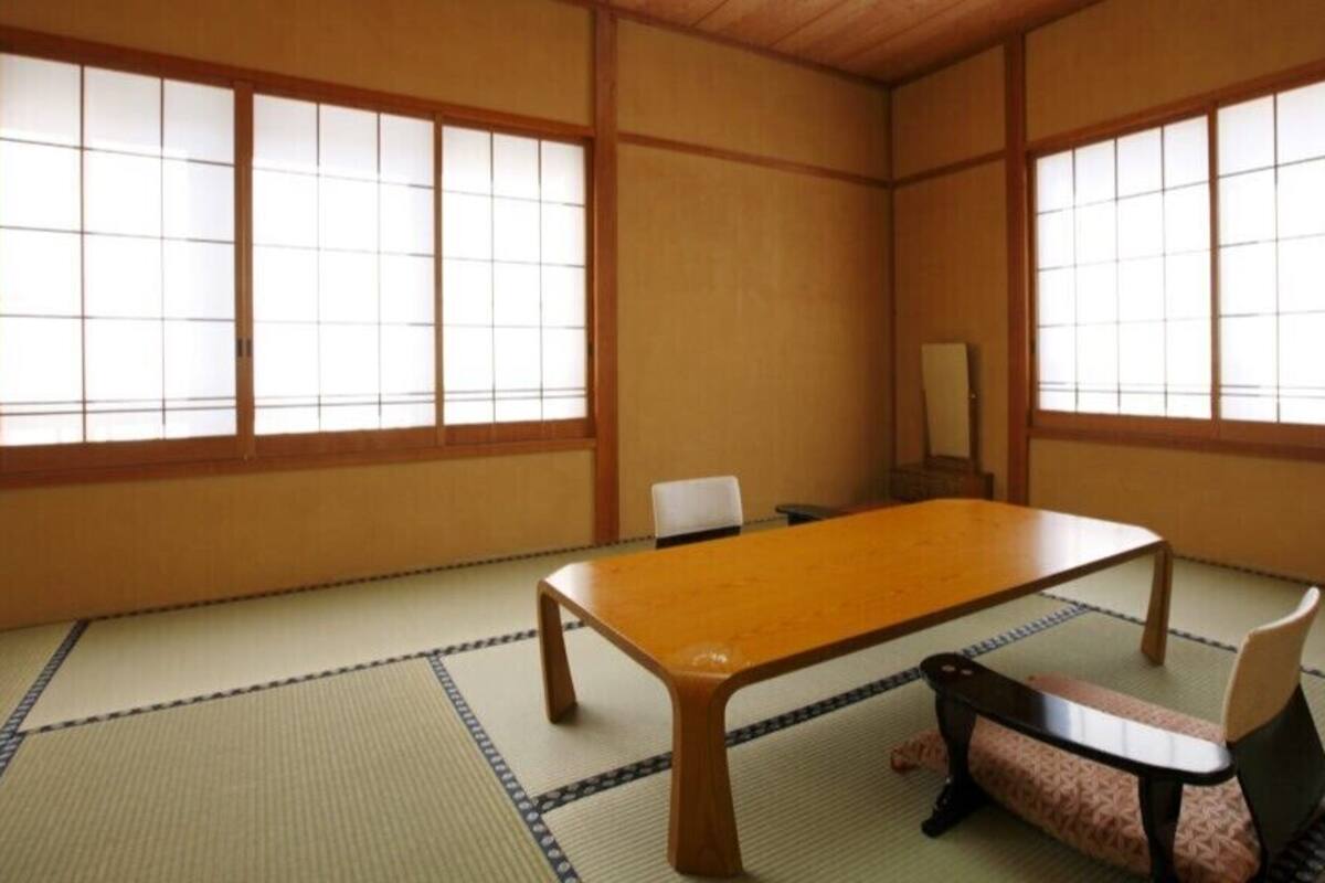 A traditional Japanese room with tatami flooring, a low table, and sliding doors.