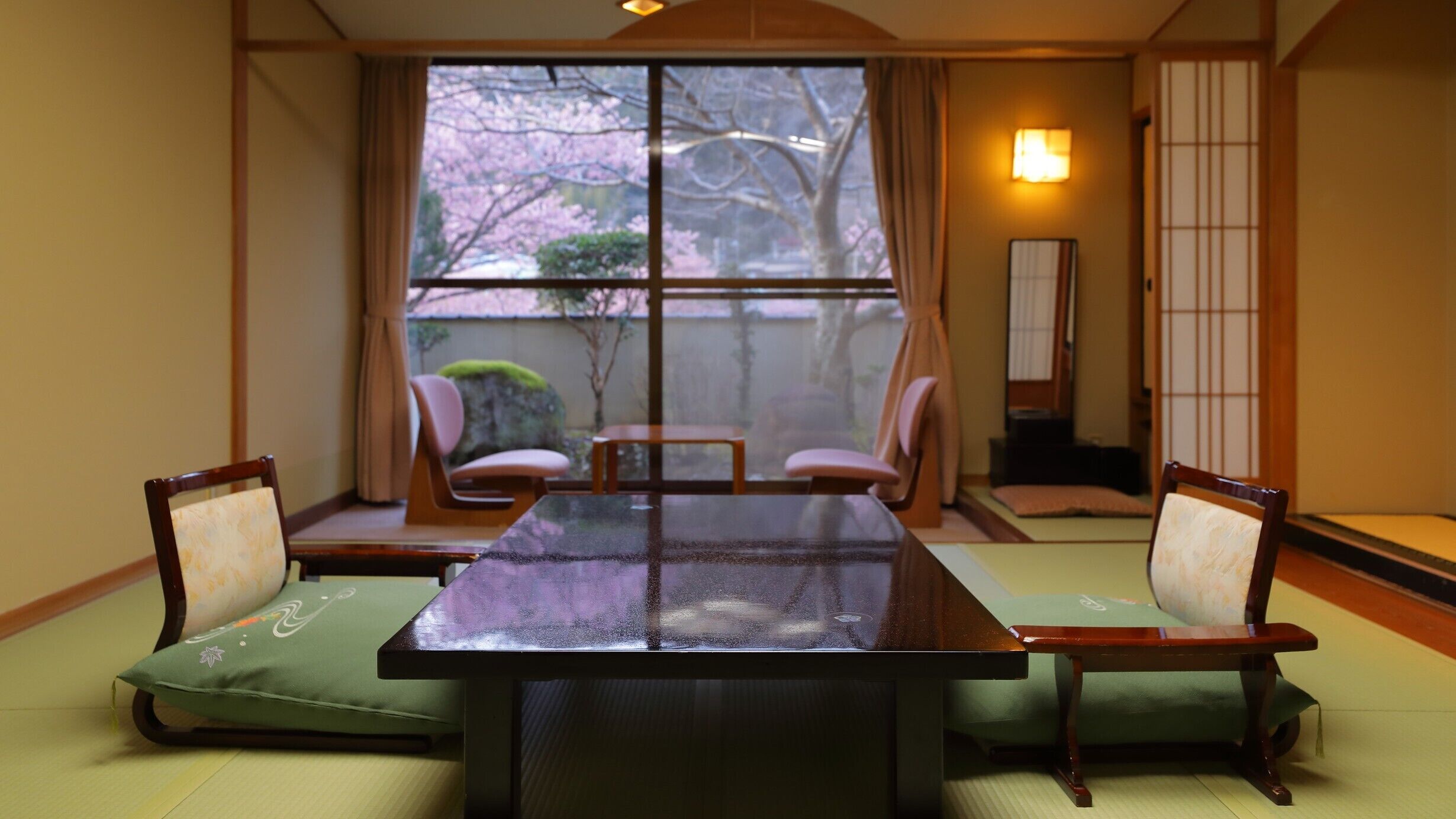 Ein traditioneller japanischer Raum mit Tatami-Boden, einem niedrigen Tisch und vier Stühlen.