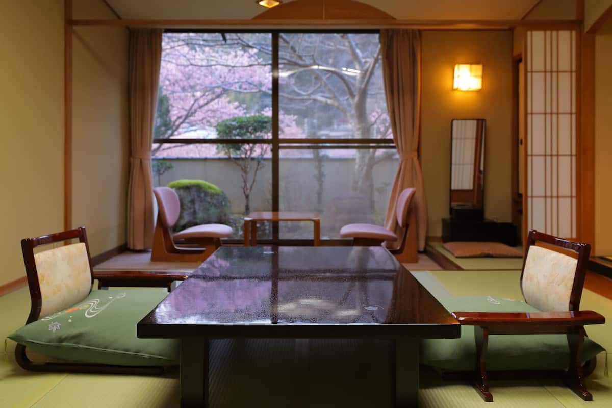 A traditional Japanese room with tatami flooring, a low table, and four chairs.