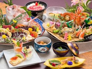 A variety of seafood dishes, including fish, shrimp, and crab, arranged on multiple plates and bowls. - Riverside Hotel Shoei (Kochi)