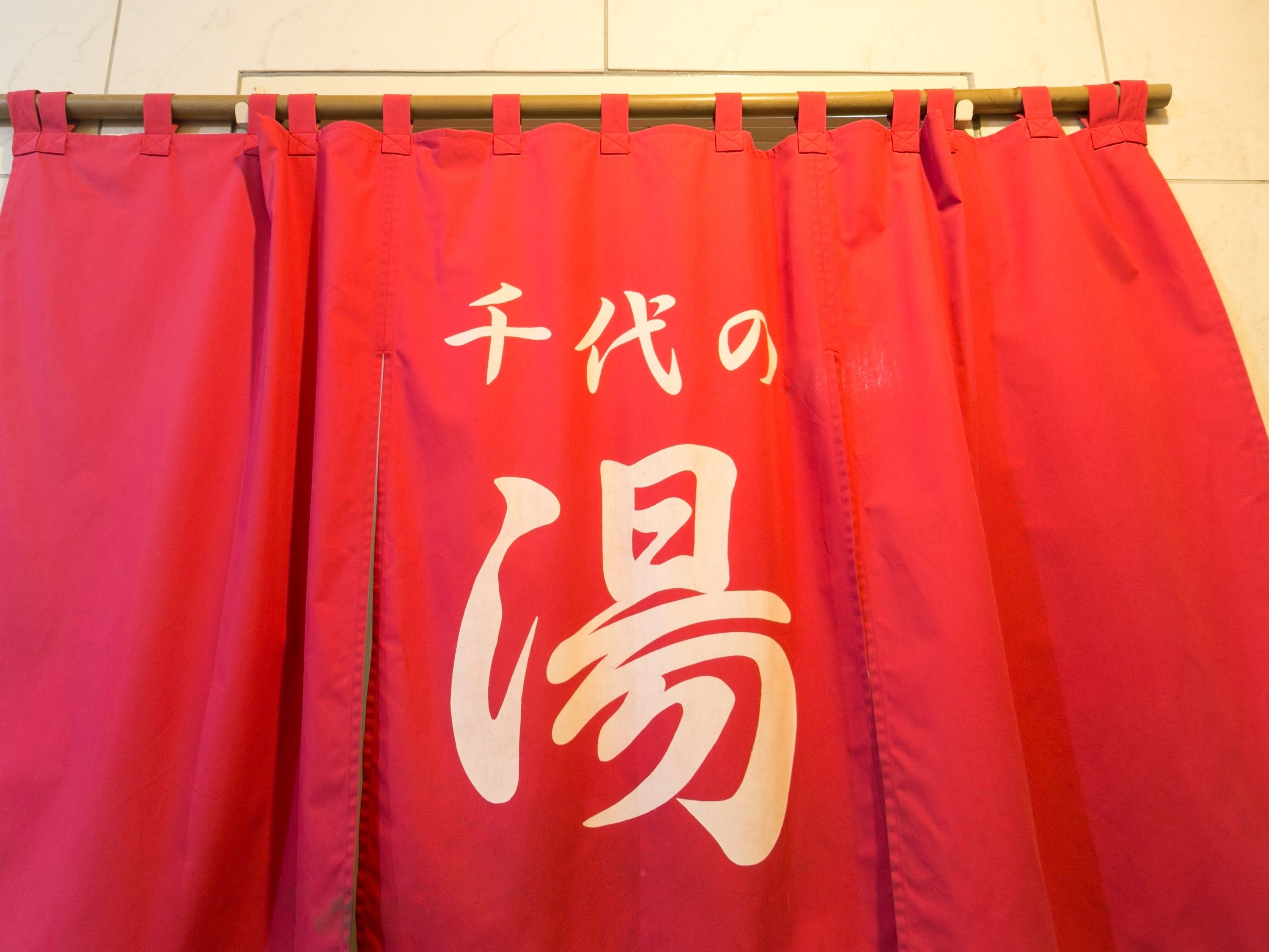 Cortina roja con caracteres japoneses blancos.