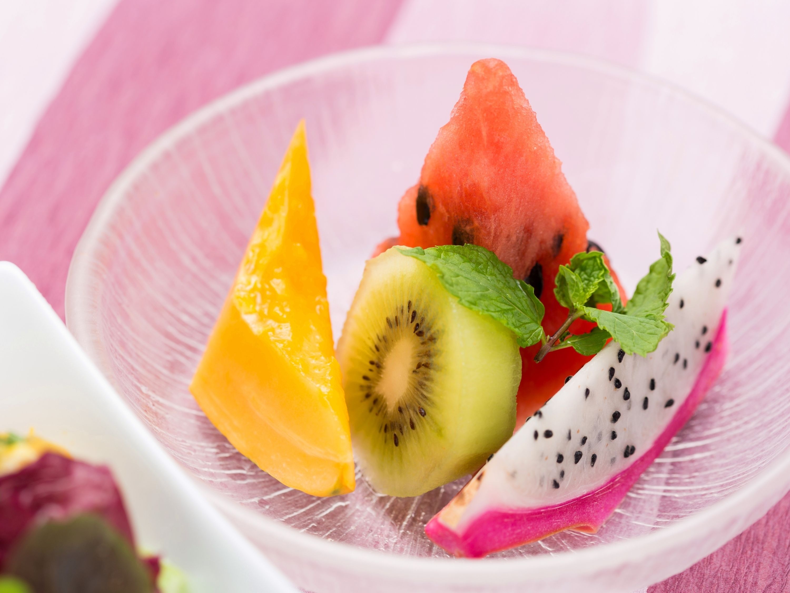 A bowl containing slices of watermelon, kiwi, dragon fruit, and mango.