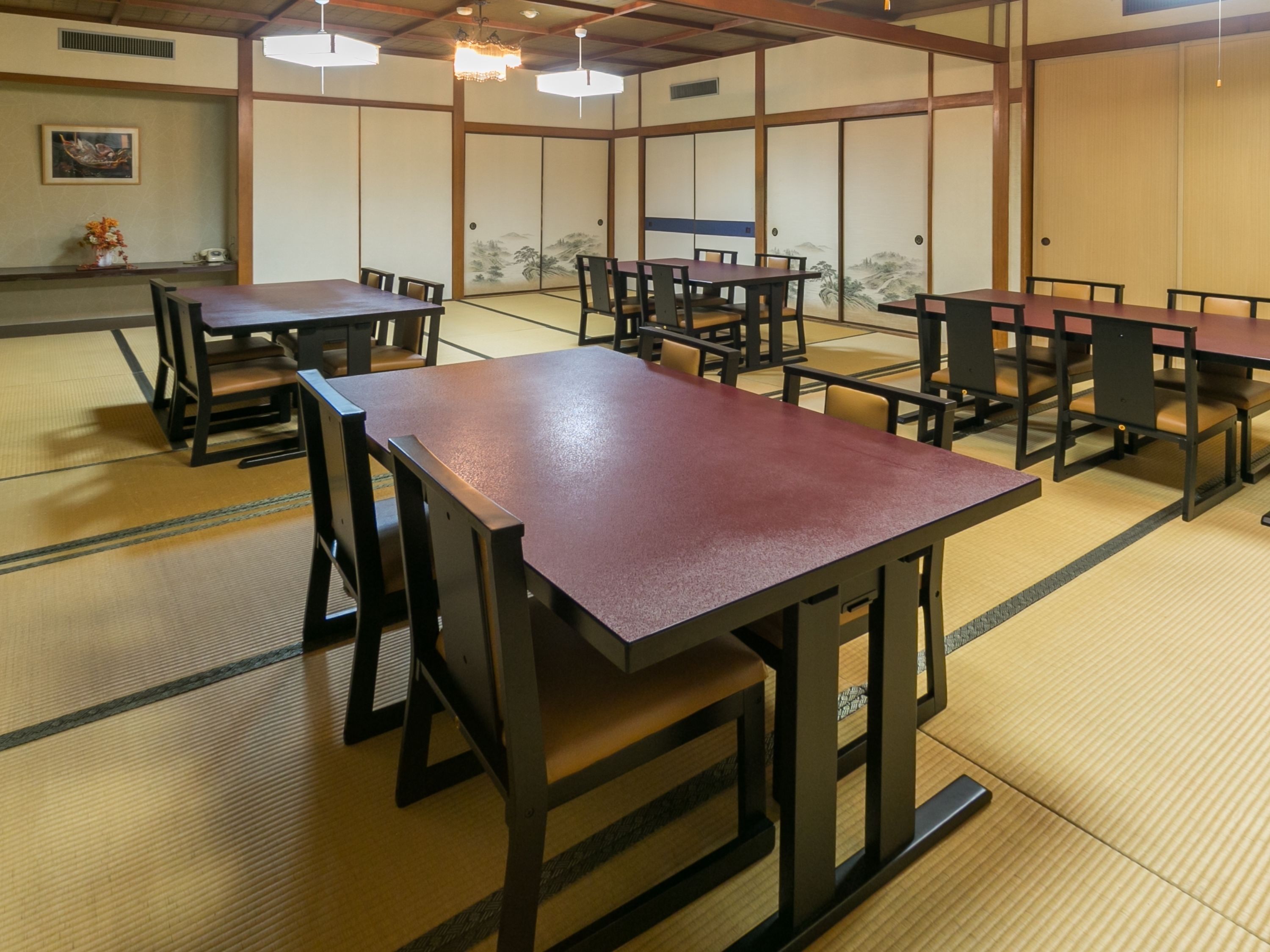 A traditional Japanese-style room with tatami flooring, wooden tables, and sliding doors.