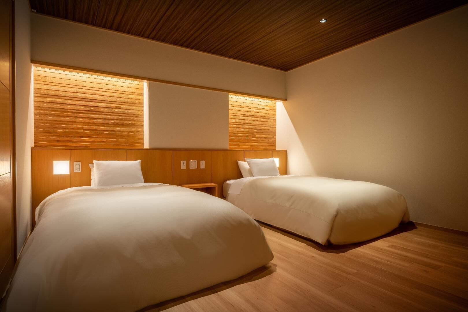 A hotel room with two beds, wooden headboards, and a sloped ceiling.