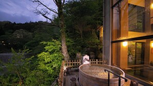 A hot spring area with a wooden deck, a large wooden tub, and a view of a forested hillside. - Hotel Sansuiso Tsuchiyu Spa Fukushima (Fukushima)