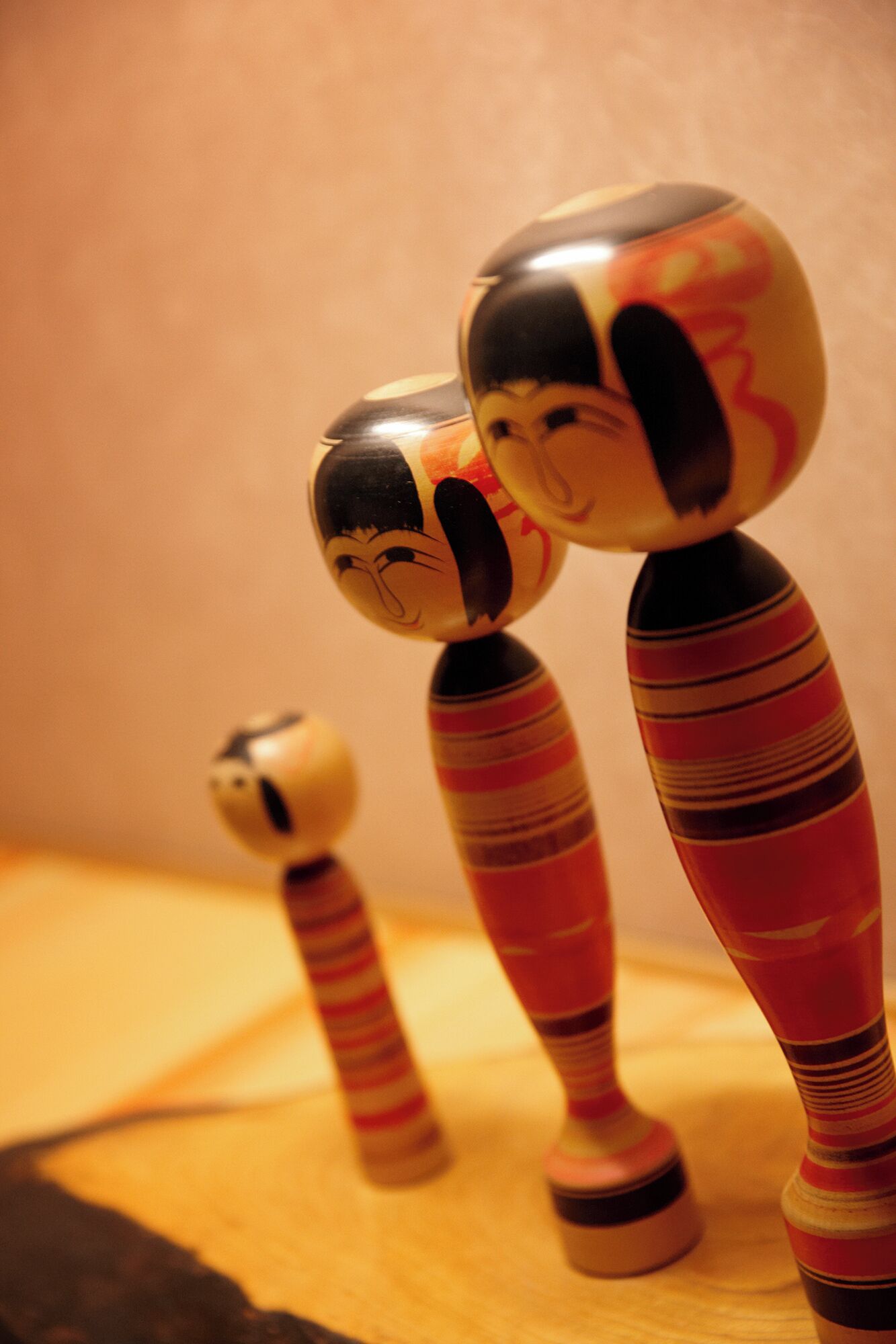 Three wooden figures with painted faces and striped bodies.