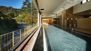 A swimming pool with a view of a waterfall and forest. - Hotel Sansuiso Tsuchiyu Spa Fukushima (Fukushima)