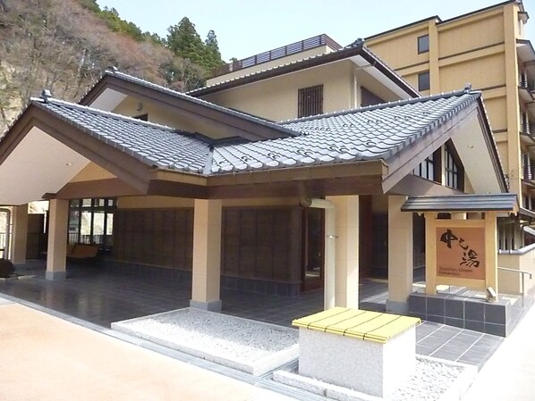 Un edificio japonés tradicional con tejado de tejas y un farol de piedra.