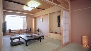 A traditional Japanese room with tatami flooring, a low table, and sliding doors. - Nishiura Grand Hotel Kikkei (Gamagori)