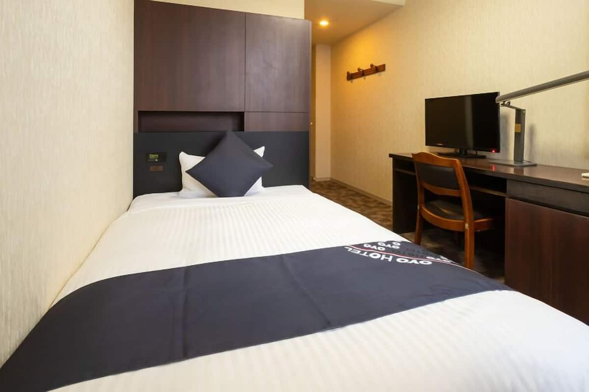 Ein Hotelzimmer mit Bett, Schreibtisch, Computer, Stuhl und Fernseher.