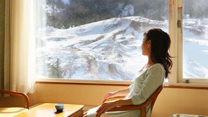 A room with a large window offering a view of a snowy landscape. - Manza Hotel Juraku (Tsumagoi)