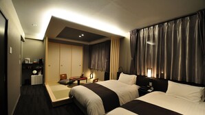 A hotel room with two beds, a desk, a chair, a small table, and a wardrobe.