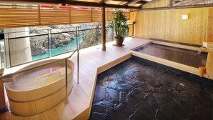 A wooden spa area with a stone hot tub and a wooden bath.