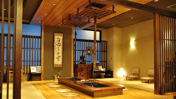 A traditional Japanese room with tatami flooring, a tea ceremony setup, and sliding doors.