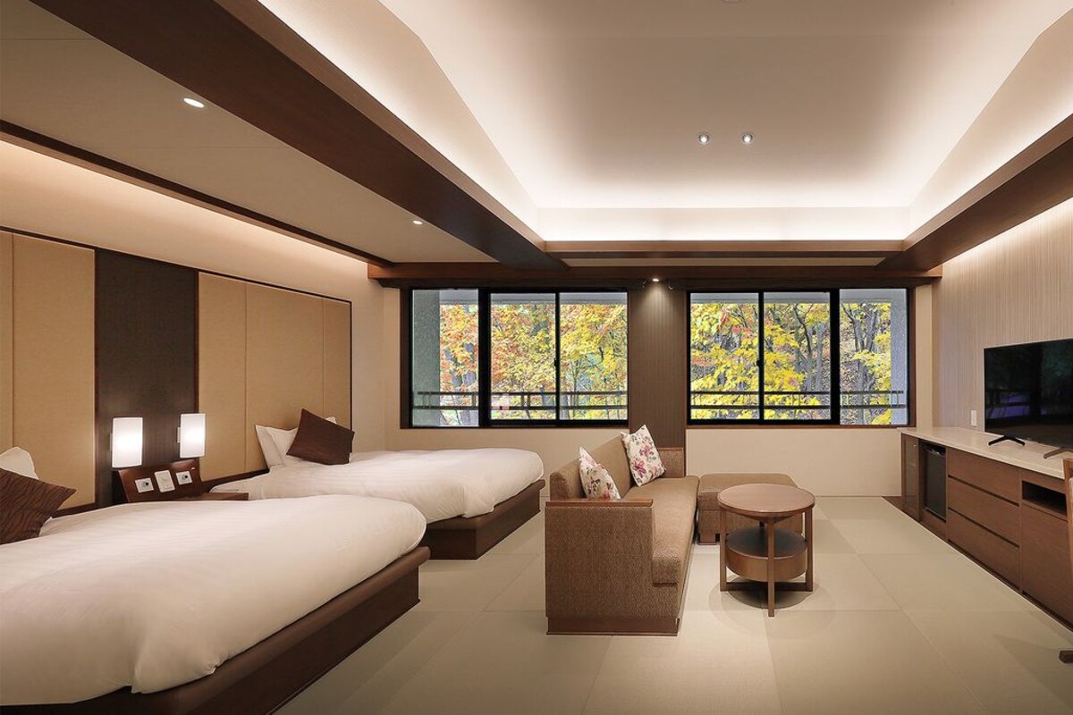 Una habitación de hotel moderna con una cama grande, un sofá, un escritorio y un televisor.