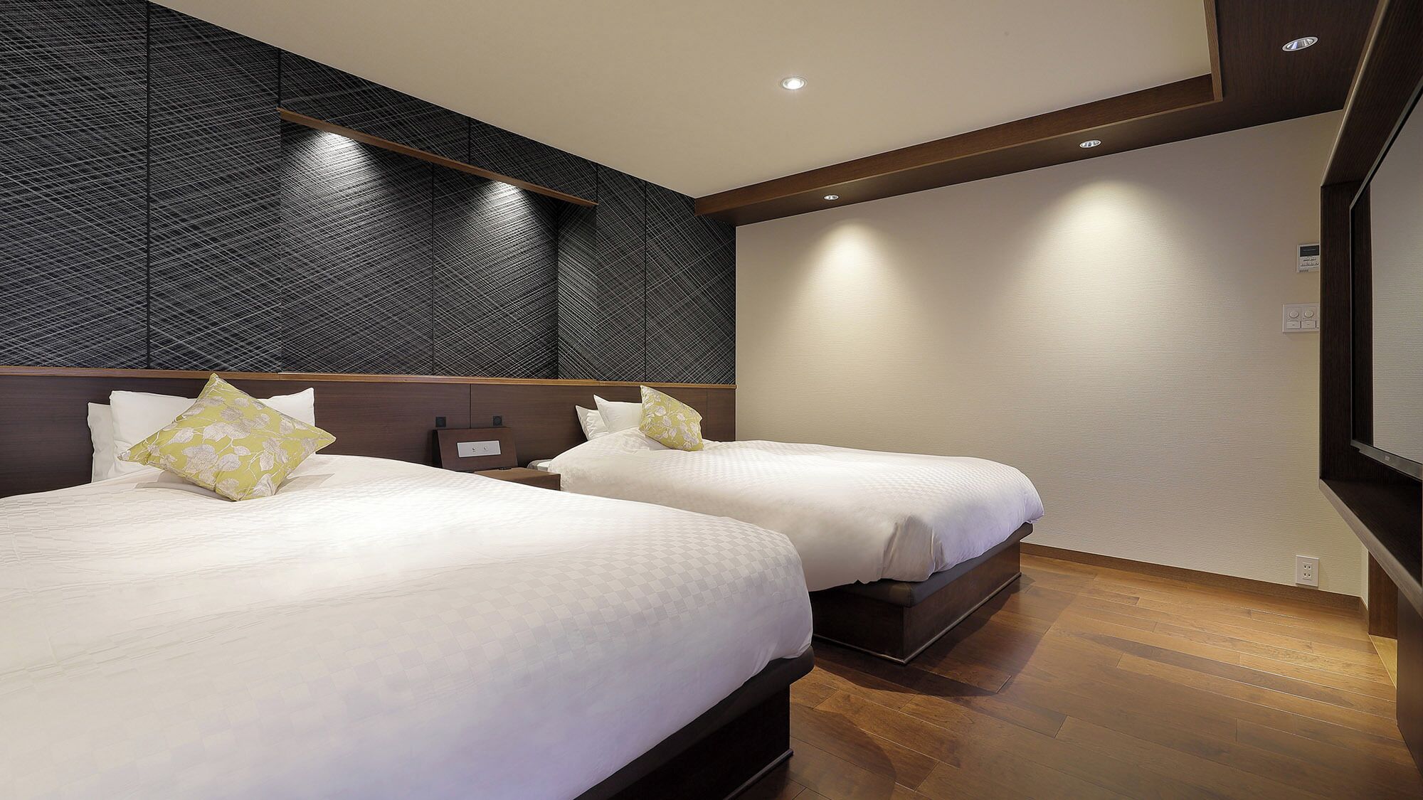 A hotel room with two beds, a dark textured wall, and a wooden floor.